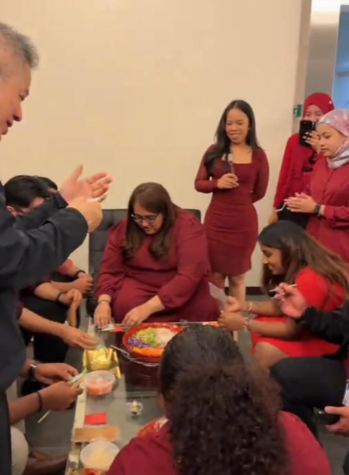 Antasis colleagues gathering around a table to toss yusheng together
