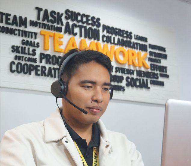 Antasis team member at work, with teamwork and collaboration on the wall behind